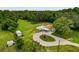 Aerial view of house with outbuildings, circular drive, lush landscaping, and lots of surrounding green space at 8540 Roseanne Blvd, New Port Richey, FL 34654