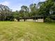 The exterior of a weathered barn with a green lawn and scattered trees at 8540 Roseanne Blvd, New Port Richey, FL 34654