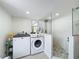 Bathroom-laundry room combo with washer/dryer and glass-enclosed shower featuring stone pebble floor at 8540 Roseanne Blvd, New Port Richey, FL 34654