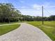 Scenic paved driveway leading to a home, surrounded by green grass and mature trees at 8540 Roseanne Blvd, New Port Richey, FL 34654