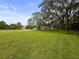 A serene view of the property featuring an expansive green lawn, mature trees, and a charming home at 8540 Roseanne Blvd, New Port Richey, FL 34654