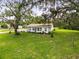 Low aerial view of house, front lawn, and trees with Spanish moss at 8540 Roseanne Blvd, New Port Richey, FL 34654