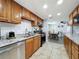 Well-lit kitchen with wooden cabinets, stainless steel appliances, and granite countertops leading to the dining area at 8540 Roseanne Blvd, New Port Richey, FL 34654