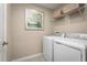Convenient laundry room featuring a modern washer and dryer, complemented by overhead storage shelves and decorative art at 8917 Waxwing Way, Parrish, FL 34219