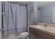 Well-lit bathroom features a shower-tub with a decorative blue shower curtain and a vanity with tan countertop at 10149 Rockbay Rd, Brooksville, FL 34601