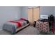Simple bedroom features a red and gray striped bed and desk with computer provides a functional space at 10149 Rockbay Rd, Brooksville, FL 34601