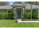 Inviting front entrance with decorative glass door, manicured shrubs, and vibrant green lawn at 10149 Rockbay Rd, Brooksville, FL 34601