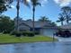 Charming single-story home with stone accents, a well-manicured lawn, and mature palm trees at 10301 Ravines Dr, New Port Richey, FL 34654