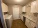 Bright laundry room with front loading washer and dryer, white cabinets, and laminate countertops at 10301 Ravines Dr, New Port Richey, FL 34654