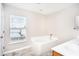 Bright bathroom featuring a tiled tub, window, tiled floors, and a vanity sink at 10386 Norvell Rd, Spring Hill, FL 34608