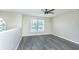 Bedroom features gray wood-look floors, a ceiling fan, and a large window that brings in ample natural light at 10386 Norvell Rd, Spring Hill, FL 34608