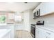 Well-lit kitchen featuring white cabinets, appliances and countertops, with tile floors and modern fixtures at 10386 Norvell Rd, Spring Hill, FL 34608