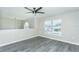Bright living room featuring gray wood-look floors, a ceiling fan, and large windows for natural light at 10386 Norvell Rd, Spring Hill, FL 34608