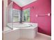 A pink bathroom with a large soaking tub and enclosed shower at 12027 Yellow Finch Ln, Trinity, FL 34655
