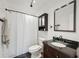 Bathroom featuring a shower with curtain, toilet, and dark wood vanity with a black granite countertop at 13001 Sawmill Way, Hudson, FL 34667