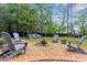 Charming backyard features a fire pit area with Adirondack chairs surrounded by mature trees at 13444 English Parrot Rd, Brooksville, FL 34614