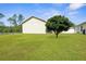 View of the spacious backyard and lawn with lush green grass and a beautiful tree at 13444 English Parrot Rd, Brooksville, FL 34614