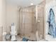 Modern bathroom featuring a glass-enclosed shower, toilet, and neutral tile at 13444 English Parrot Rd, Brooksville, FL 34614