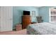 Cozy bedroom with blue walls, a wooden dresser with a TV, and a comfortable patterned bed at 13444 English Parrot Rd, Brooksville, FL 34614