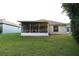 Exterior shot of the screened in porch and home with lush green grass at 14112 Whitecap Ave, Hudson, FL 34667