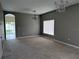 Spacious living room with neutral-colored walls, carpeted floor, window, chandelier, and patio access at 15160 Durango Cir, Brooksville, FL 34604