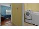 Bright laundry room with modern washer and dryer next to bedroom with blue walls and wood-look flooring at 15287 Coot Rd, Weeki Wachee, FL 34614