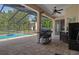 This covered patio features an outdoor grill, a ceiling fan, and a view of the screened-in pool at 15287 Coot Rd, Weeki Wachee, FL 34614