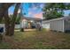 Backyard patio features outdoor seating under a covered area, complemented by a well-kept lawn and a shed for storage at 1601 E 98Th Ave, Tampa, FL 33612