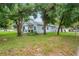 The light blue home has a yellow door and is shaded by mature trees at 1601 E 98Th Ave, Tampa, FL 33612