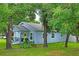 Light blue home with a yellow door framed by mature trees and green lawn at 1601 E 98Th Ave, Tampa, FL 33612