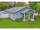 An eye-level exterior shows a light blue house with a yellow door surrounded by greenery at 1601 E 98Th Ave, Tampa, FL 33612