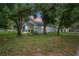 The light blue house has a yellow door and mature trees and is framed by the sunset at 1601 E 98Th Ave, Tampa, FL 33612