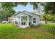 A light blue house with a yellow door has a cozy front porch with lush landscaping at 1601 E 98Th Ave, Tampa, FL 33612