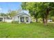 Charming home featuring a cheerful yellow door, cozy porch, and lush green lawn at 1601 E 98Th Ave, Tampa, FL 33612