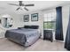 Carpeted bedroom with ceiling fan, modern art, bedside table and a queen bed with plenty of natural light at 17316 Cruiser Bnd, Land O Lakes, FL 34638