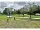 Open dog park with a walking path, chairs, landscaping, and equipment for dogs at 17316 Cruiser Bnd, Land O Lakes, FL 34638