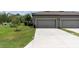 View of the two car gray garage with a long concrete driveway and green lawn at 17316 Cruiser Bnd, Land O Lakes, FL 34638