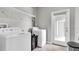 Efficient laundry room equipped with a washer, dryer, storage shelf, and access to an outdoor patio at 17316 Cruiser Bnd, Land O Lakes, FL 34638