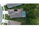 Aerial view of a home with a screened in pool, lush trees and well maintained lawn at 17679 Garsalaso Cir, Brooksville, FL 34604