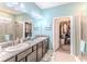 Bright bathroom featuring double sinks, granite countertop, and a walk-in closet for storage at 17679 Garsalaso Cir, Brooksville, FL 34604