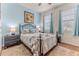 Cozy bedroom with blue walls, a metal frame bed, two windows with curtains, and a neutral area rug at 17679 Garsalaso Cir, Brooksville, FL 34604