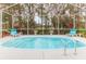 Inviting pool inside screened enclosure, with chairs for lounging and views of the wooded backyard at 17679 Garsalaso Cir, Brooksville, FL 34604