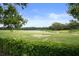 Scenic view of the meticulously maintained golf course with a sand trap, pond, and mature trees at 17727 Garsalaso Cir, Brooksville, FL 34604