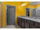 Bright bathroom features a granite countertop double sink vanity, with a view to the walk-in closet and shower at 17843 Garsalaso Cir, Brooksville, FL 34604