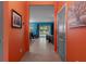 Vibrant hallway with orange walls, tiled floors, and a view into the living and dining areas at 17843 Garsalaso Cir, Brooksville, FL 34604