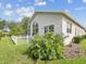 Exterior shot of backyard featuring blue flowers, white picket fence, and screened patio at 18845 Fairway Green Dr, Hudson, FL 34667