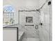 Modern bathroom featuring a glass enclosed shower with marble style tile, niche, bench, and an arched window at 18845 Fairway Green Dr, Hudson, FL 34667