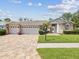 Charming single-story home with a well-manicured lawn, brick accents, three-car garage and a brick paver driveway at 18845 Fairway Green Dr, Hudson, FL 34667