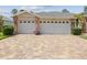 Three-car garage with brick accents and a colorful brick paver driveway at 18845 Fairway Green Dr, Hudson, FL 34667