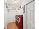 Functional laundry room equipped with red front loading washer and dryer, white cabinets, and tile floors at 18845 Fairway Green Dr, Hudson, FL 34667